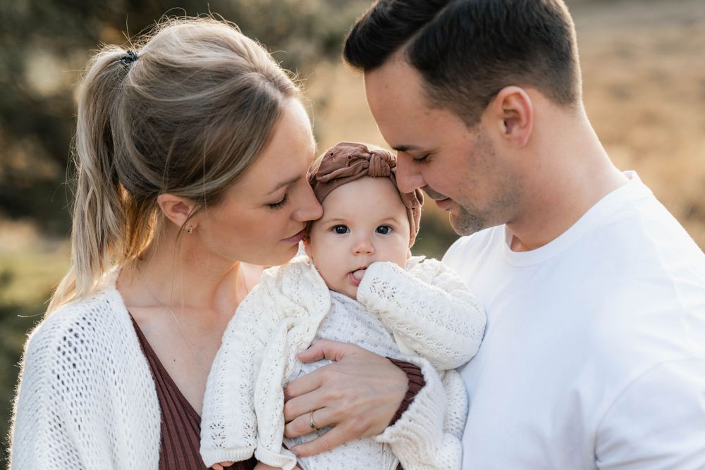 A close-up family portrait showing tender affection outdoors at sunset.