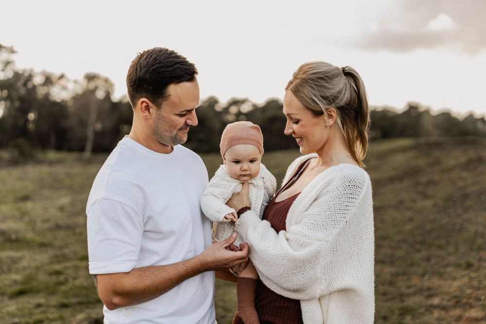 A warm family moment captured against rolling hills at dusk.