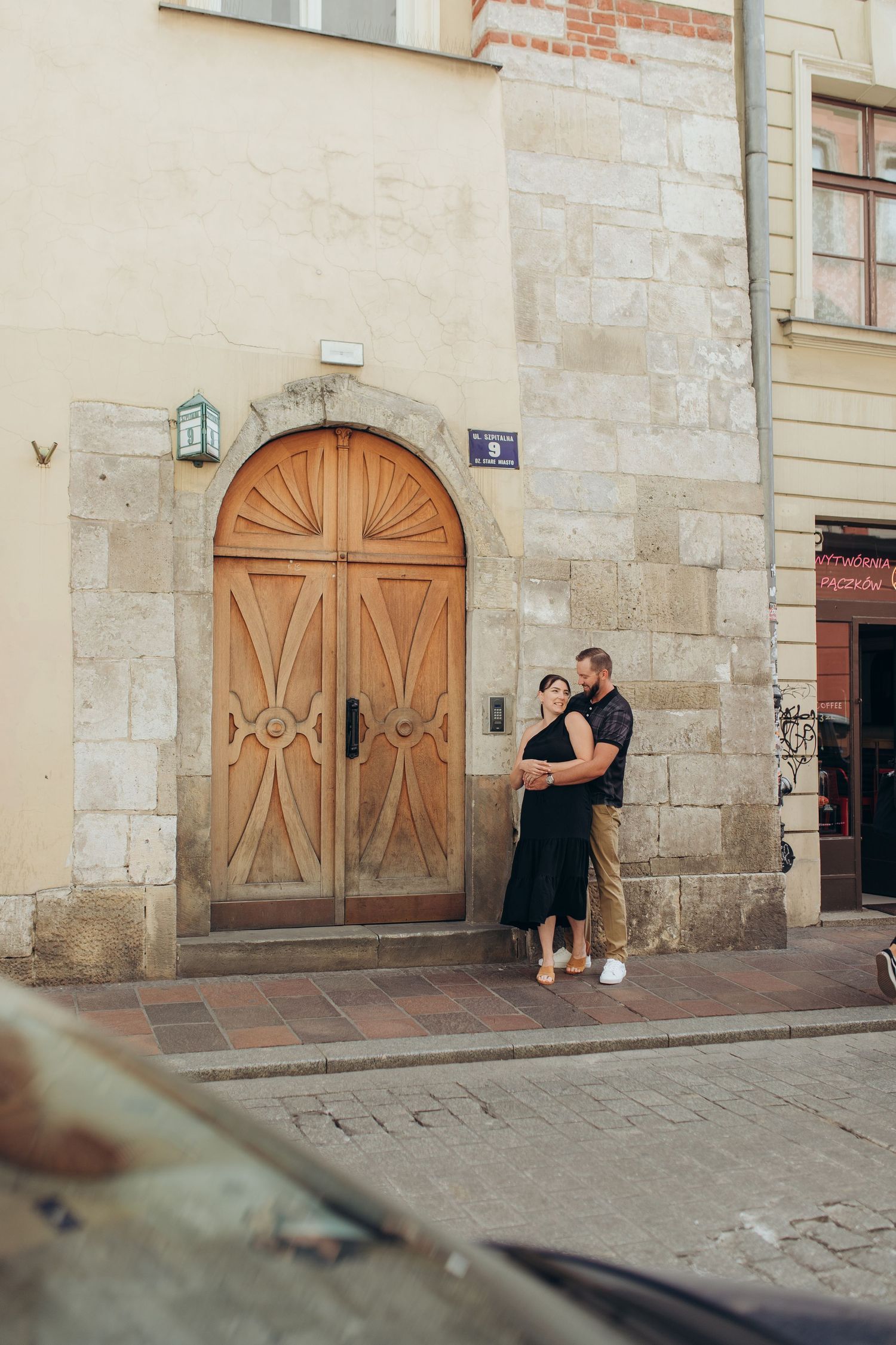 Couple sharing a tender moment by vintage wooden door on European street corner.