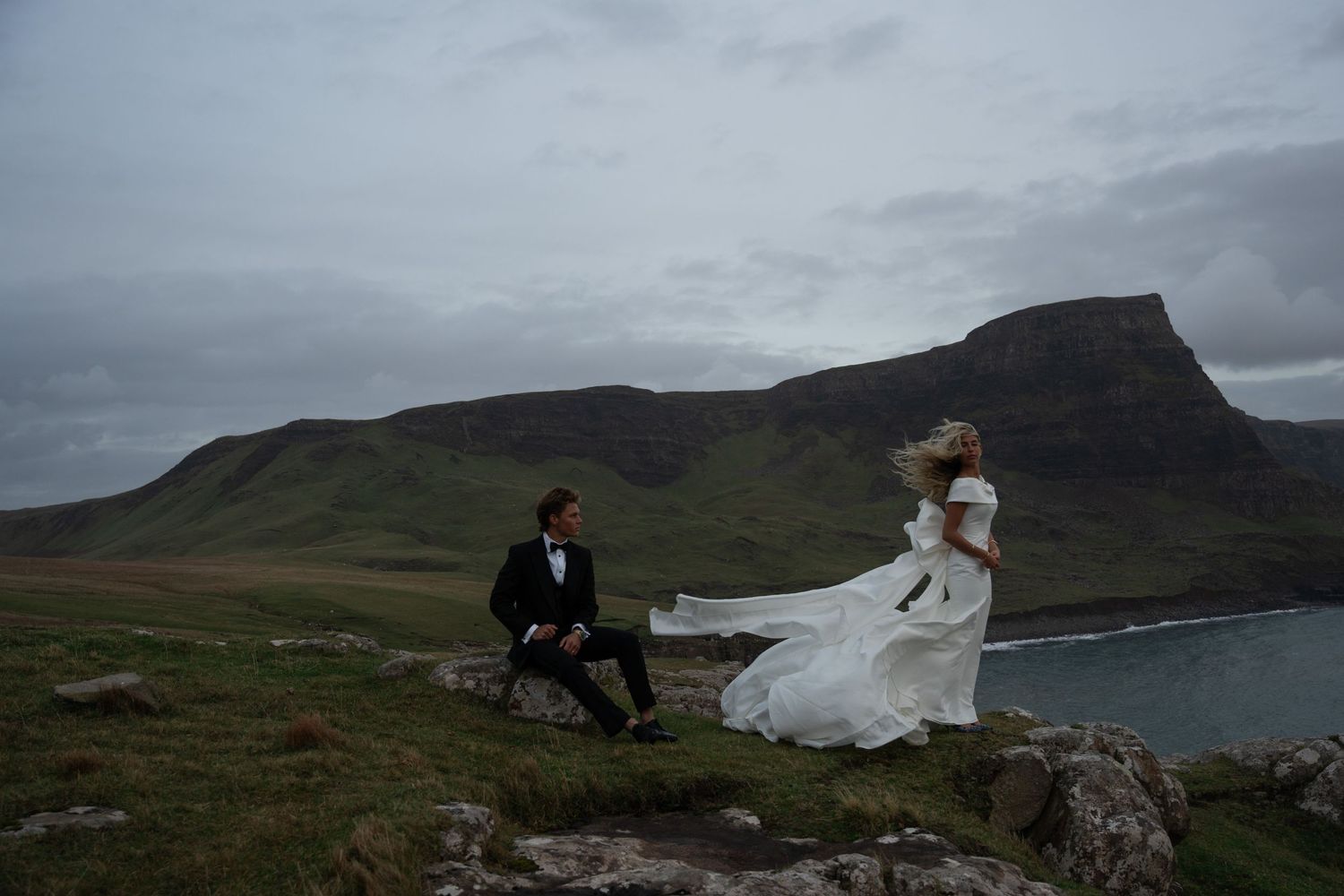 Couple on the Isle of Skye, captured in dramatic wedding photos with rugged cliffs, moody skies, and a timeless, cinematic atmosphere.