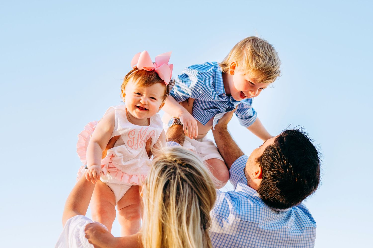 best hawaii family photographer kihei wailea kaanapali makena Playful family lifestyle portraits against a bright blue sky background.