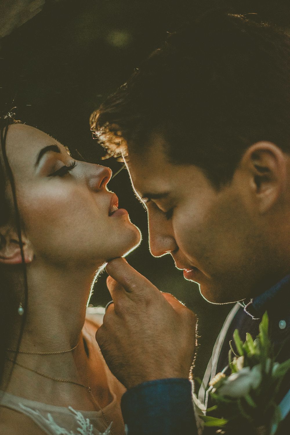 An intimate close-up photo of a romantic couple in warm sunset lighting with soft focus and dreamy atmosphere.