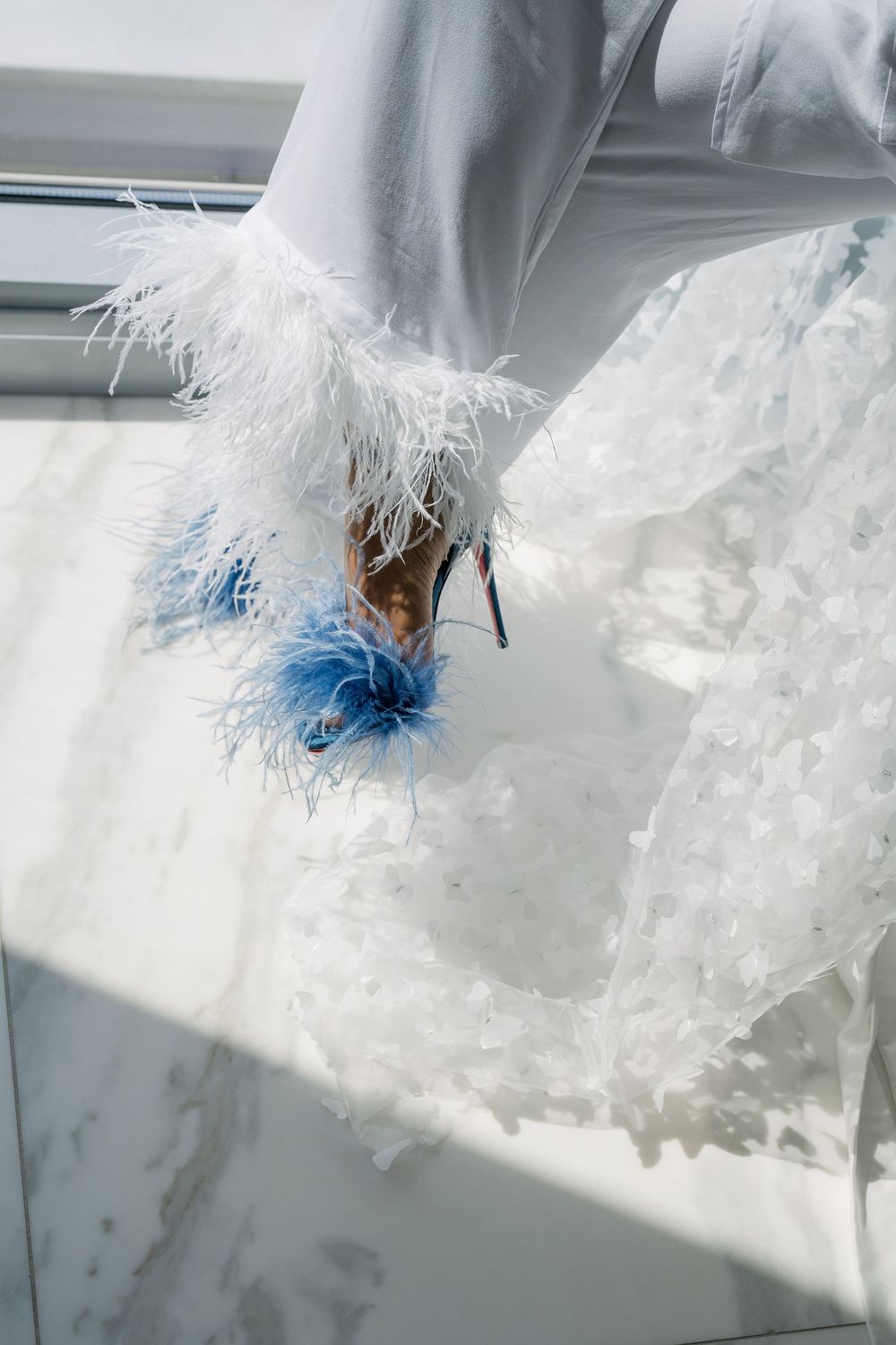 Wedding shoes with blue feather details and white fabric draped elegantly.