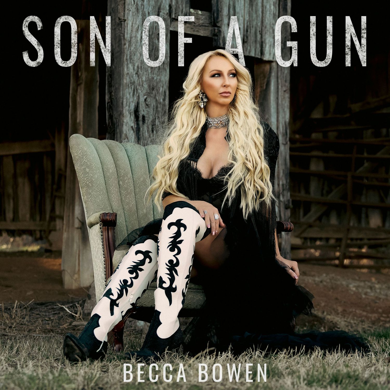Country album cover for "Son of a Gun" with artist Becca Bowen in black dress and embroidered boots against rustic barn.