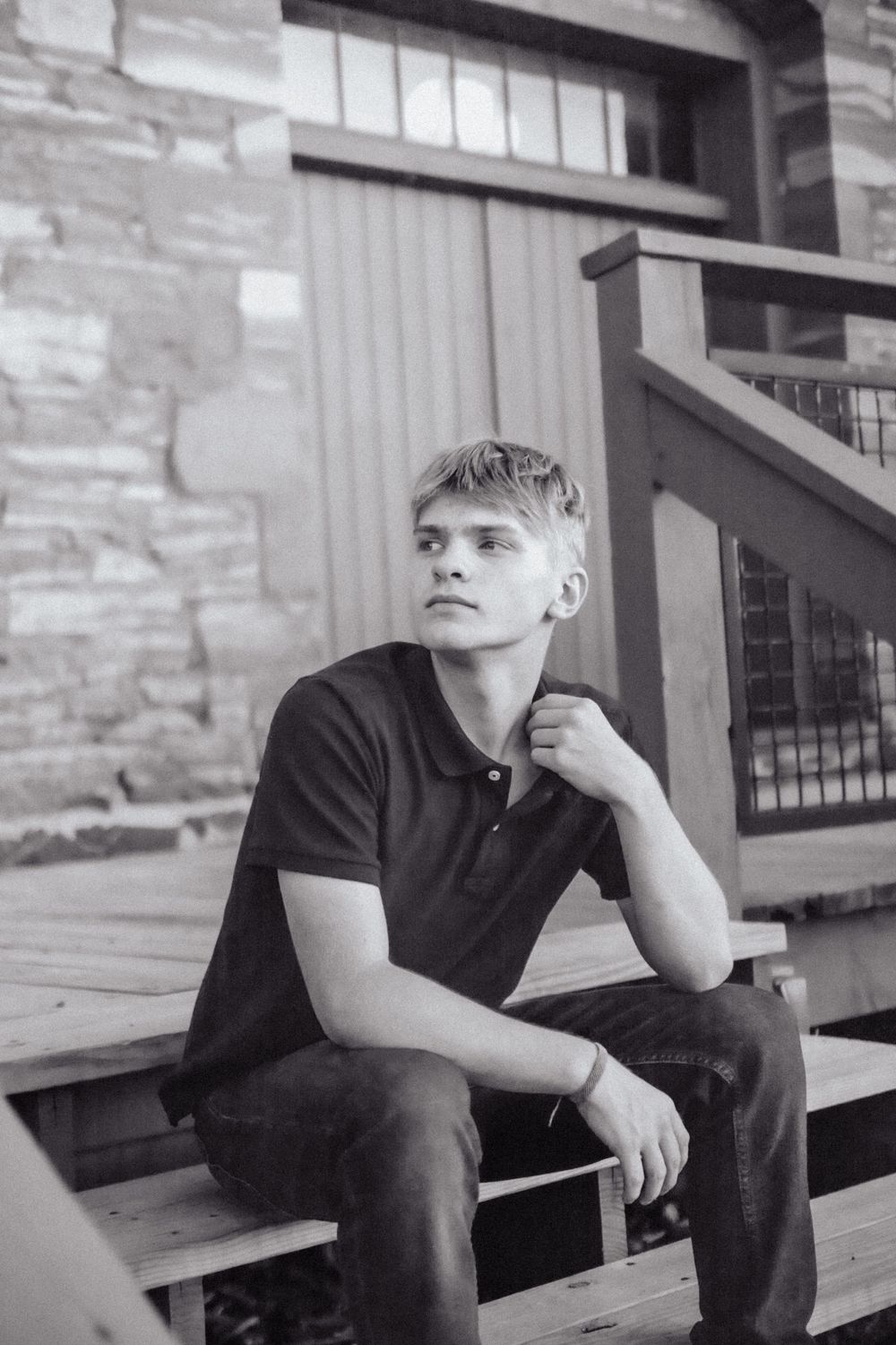 A black and white portrait of someone sitting thoughtfully on wooden steps.