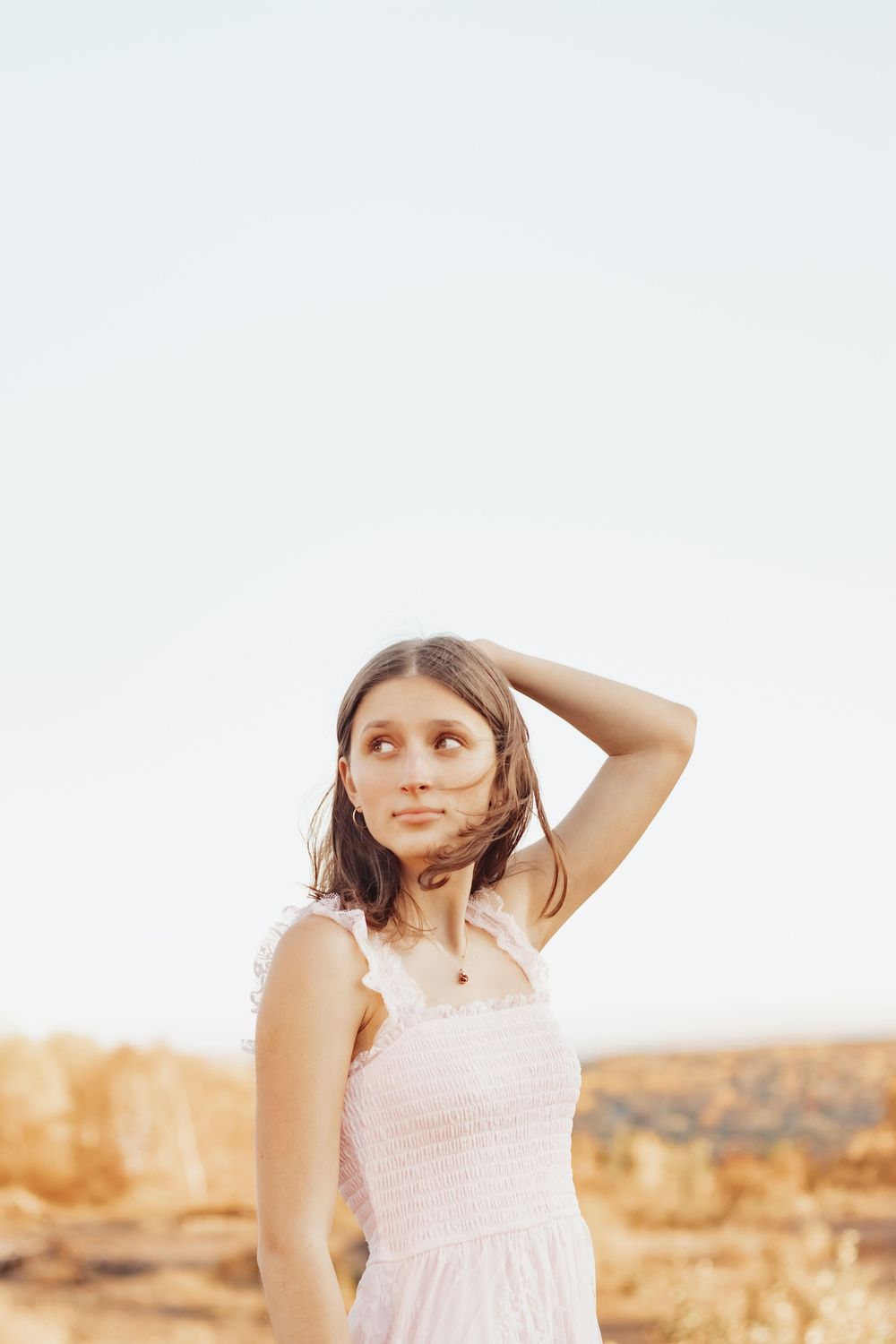 A dreamy sunset portrait in a white dress against a desert landscape.