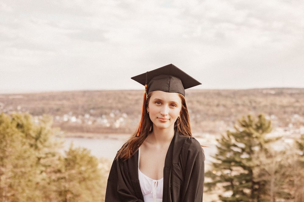 Houghton High School graduate in cap and gown standing on Quincy Hill in Hancock, Michigan. Overlooking Michigan Tech University.