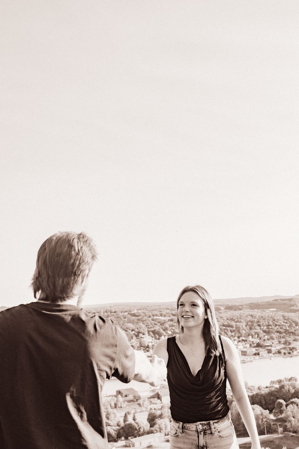 A couple sharing a joyful moment on a scenic overlook during golden hour.