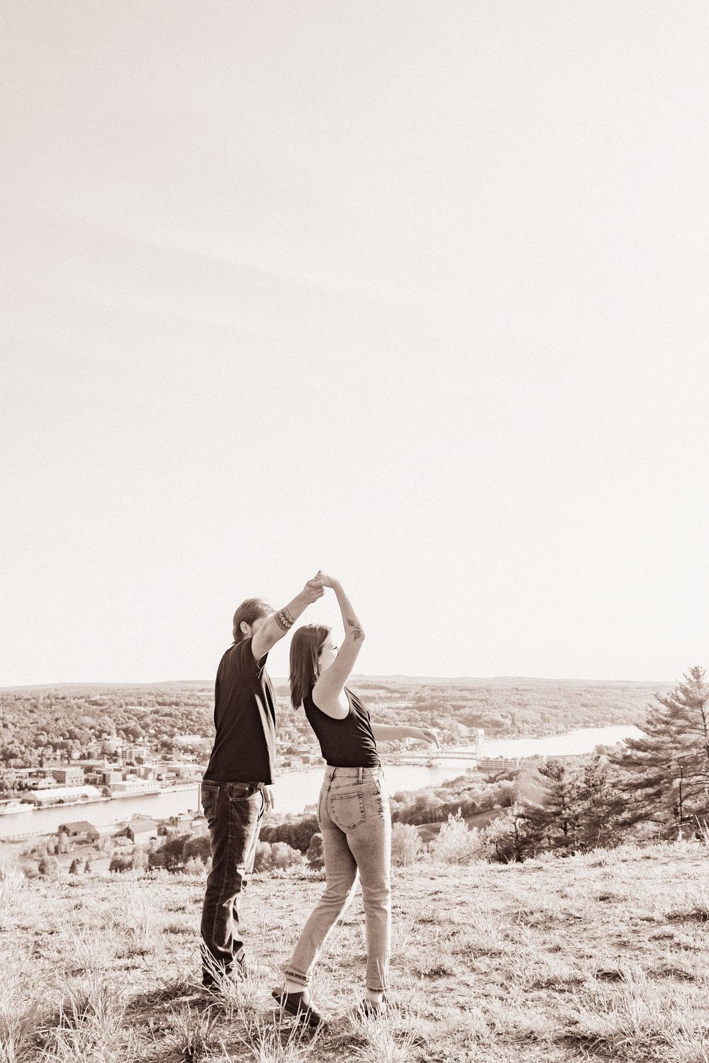 Two people dancing together on a hilltop with a sweeping valley vista.