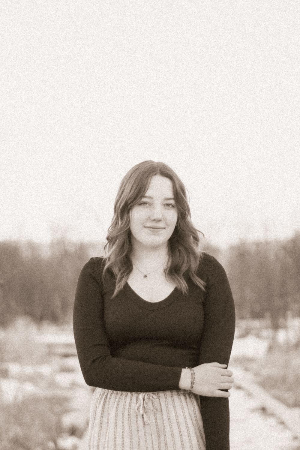 Winter portrait in black and white tones with snowy landscape in background.