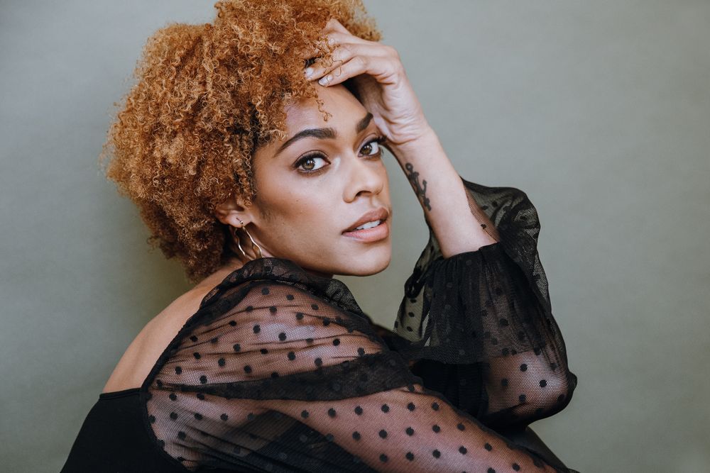 Studio portrait with polka dot sheer sleeves against neutral background.