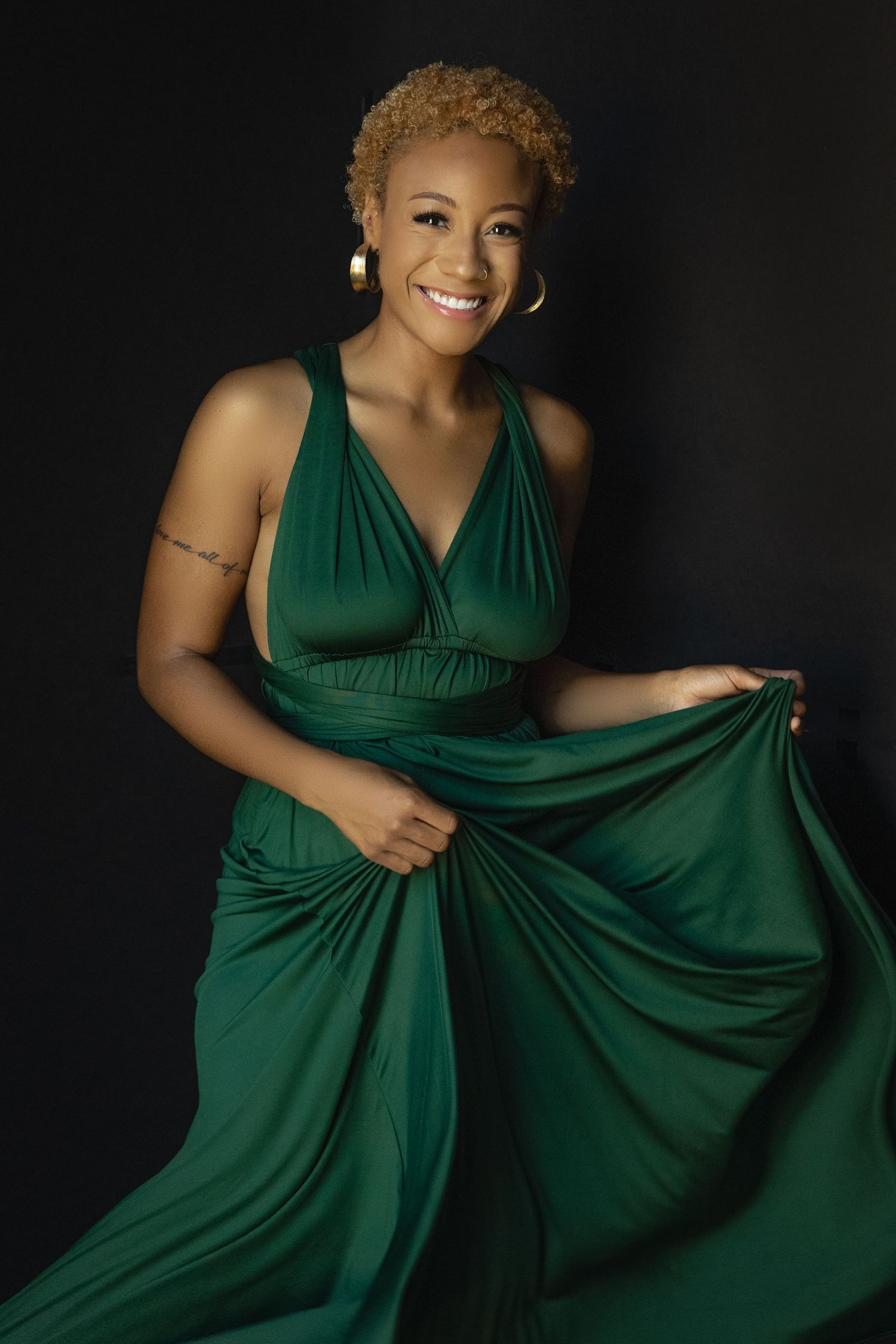 Elegant portrait in flowing emerald green dress against dark background.