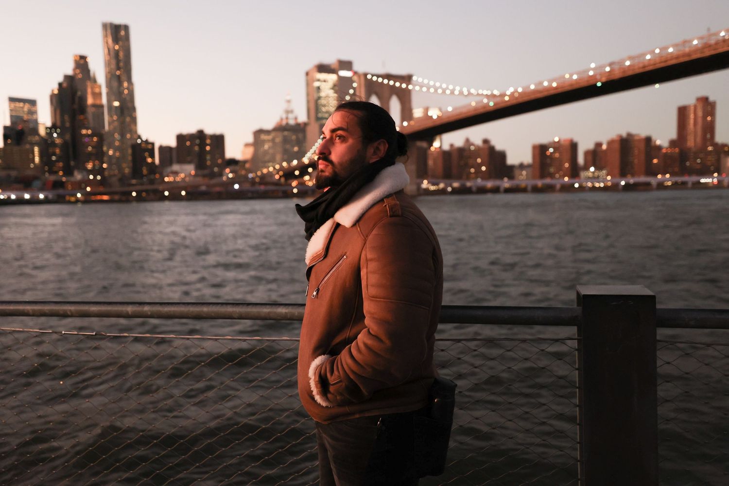 Urban portrait at dusk with city skyline and bridge in background.