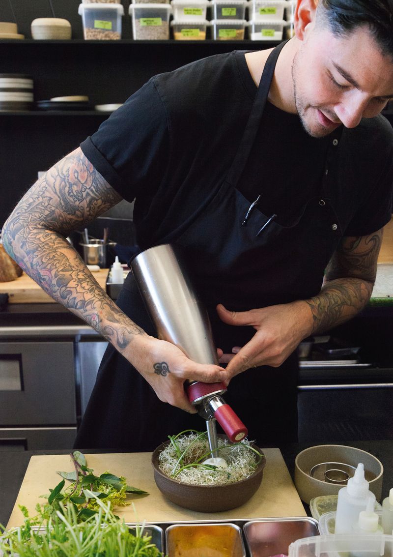Young stylish chef plating a creative dish in the kitchen