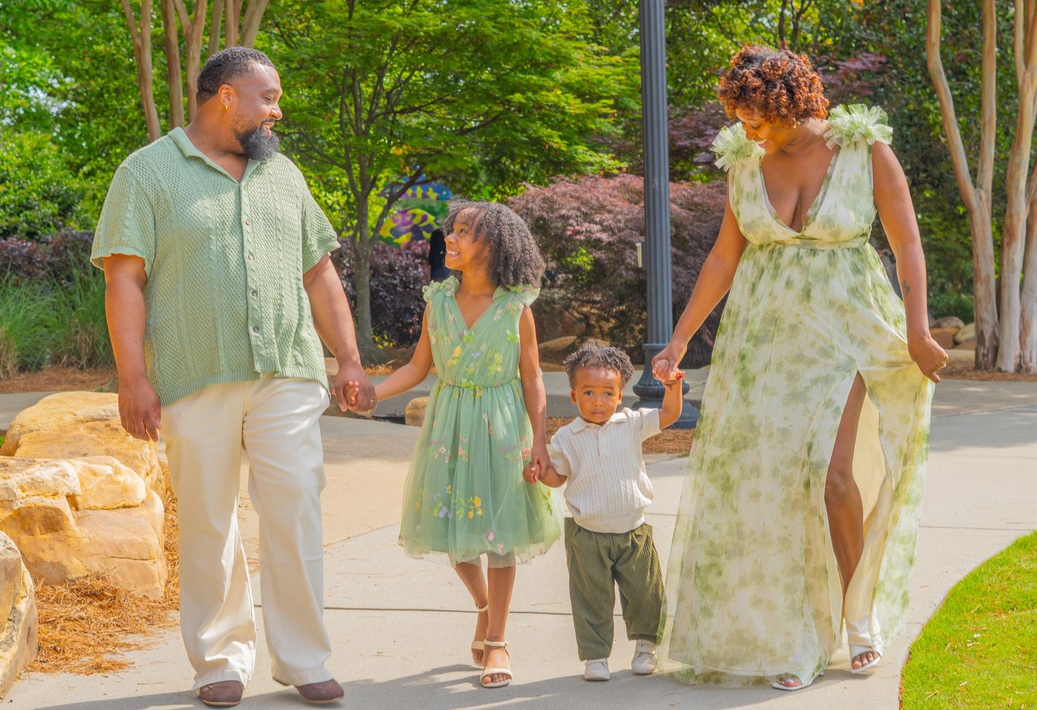 Black and white photo of a family walking together outdoors, with parents and two children holding hands in a line.