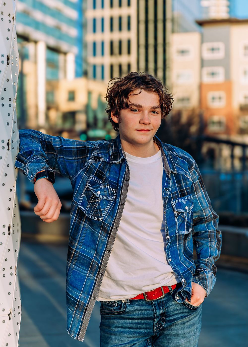 Stylish denim jacket and jeans outfit against urban backdrop with white columns.