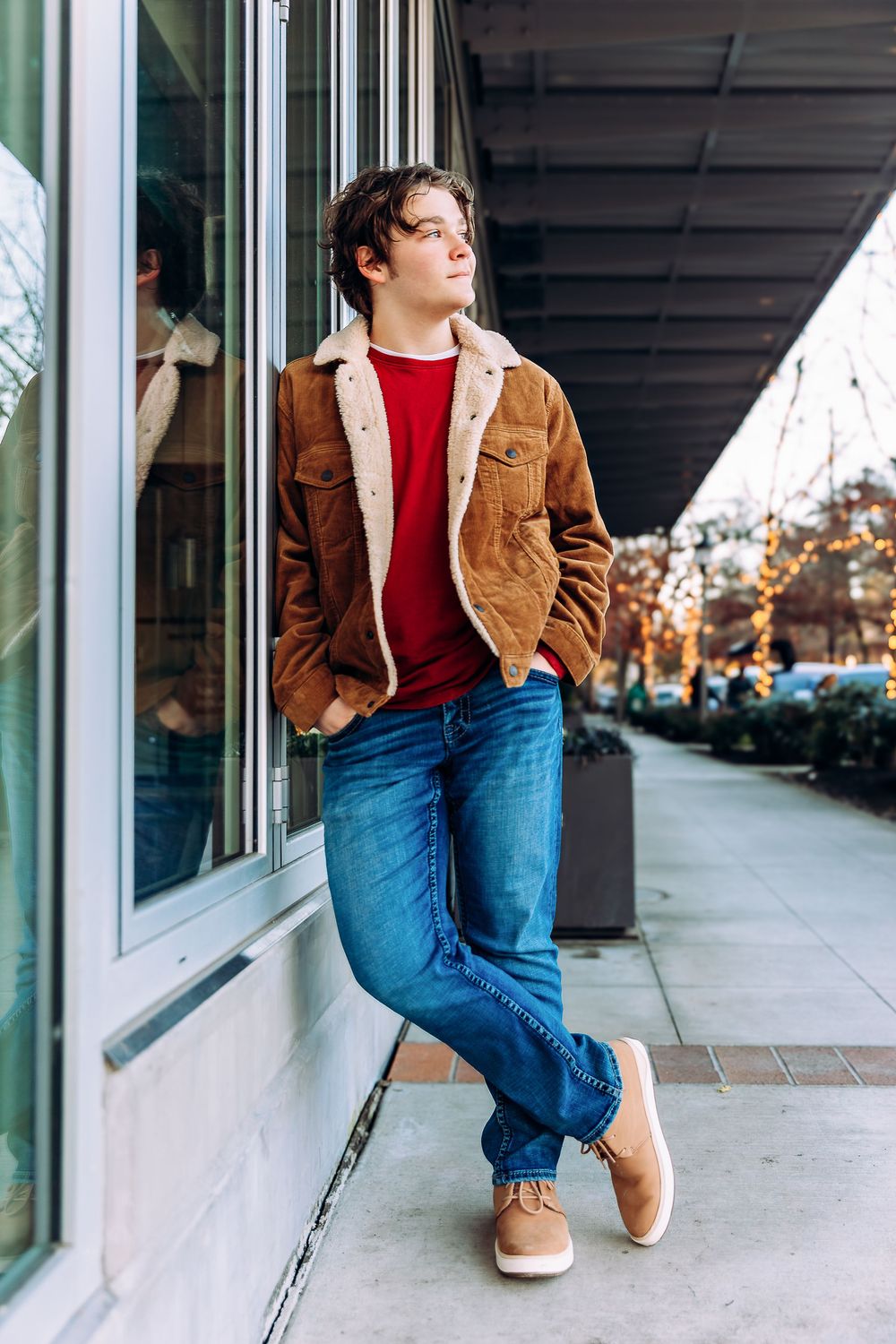 Casual look featuring brown corduroy jacket and jeans in front of storefront windows.