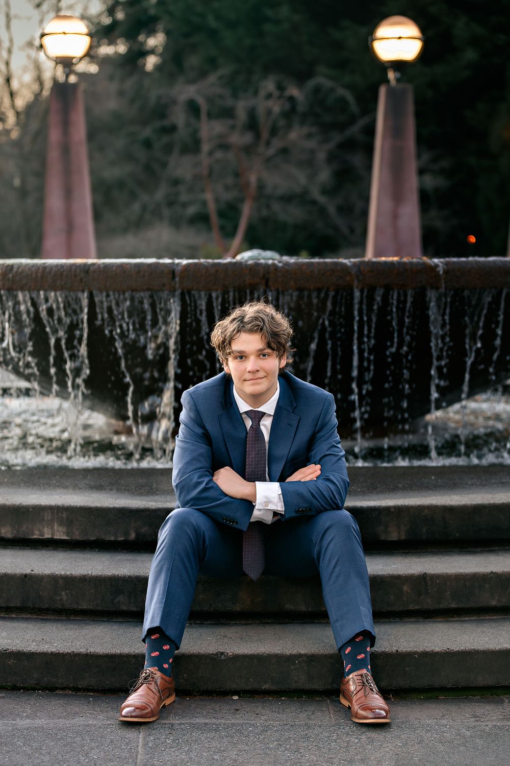 Evening portrait session by an illuminated fountain with modern architecture in the background.