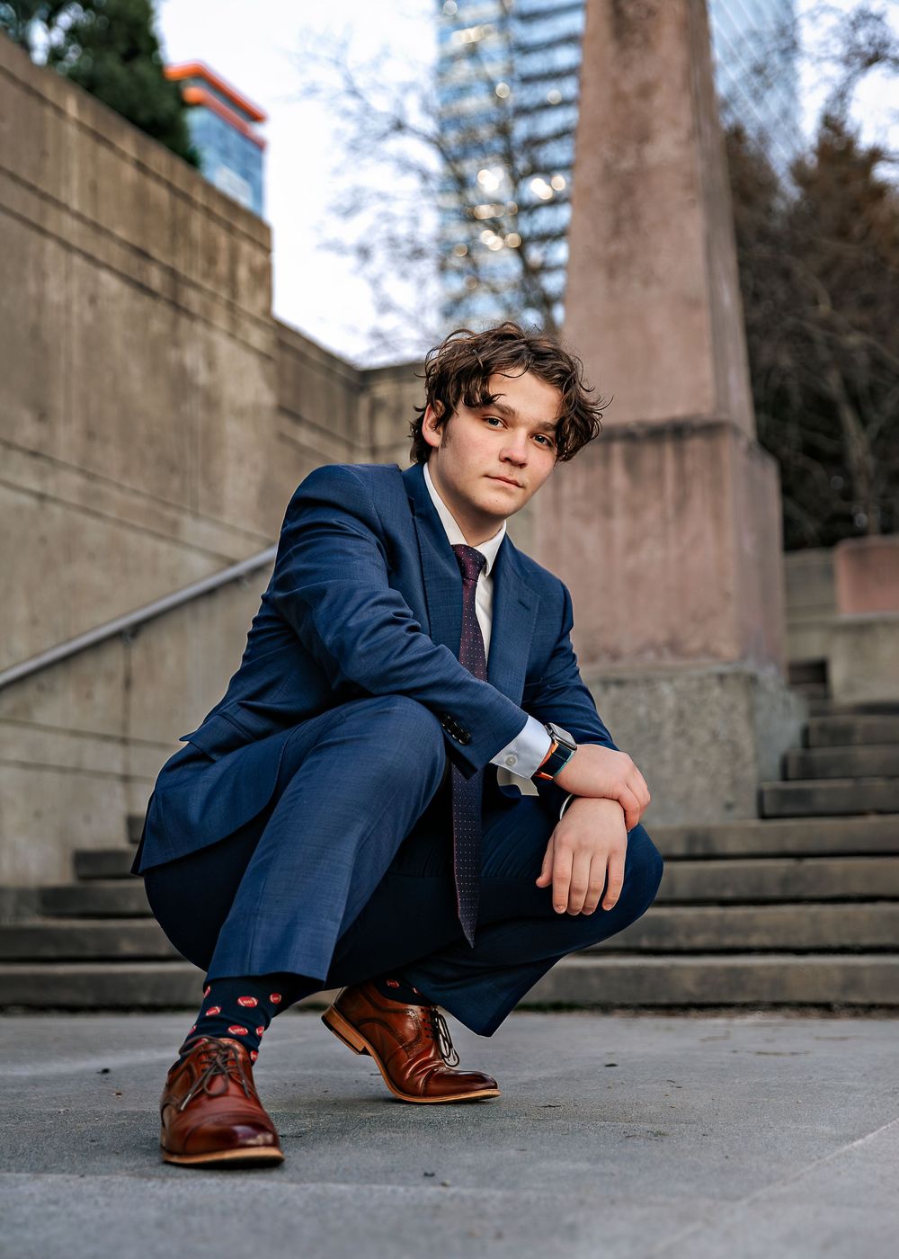 Stylish portrait session on concrete steps featuring a navy suit and brown leather shoes.