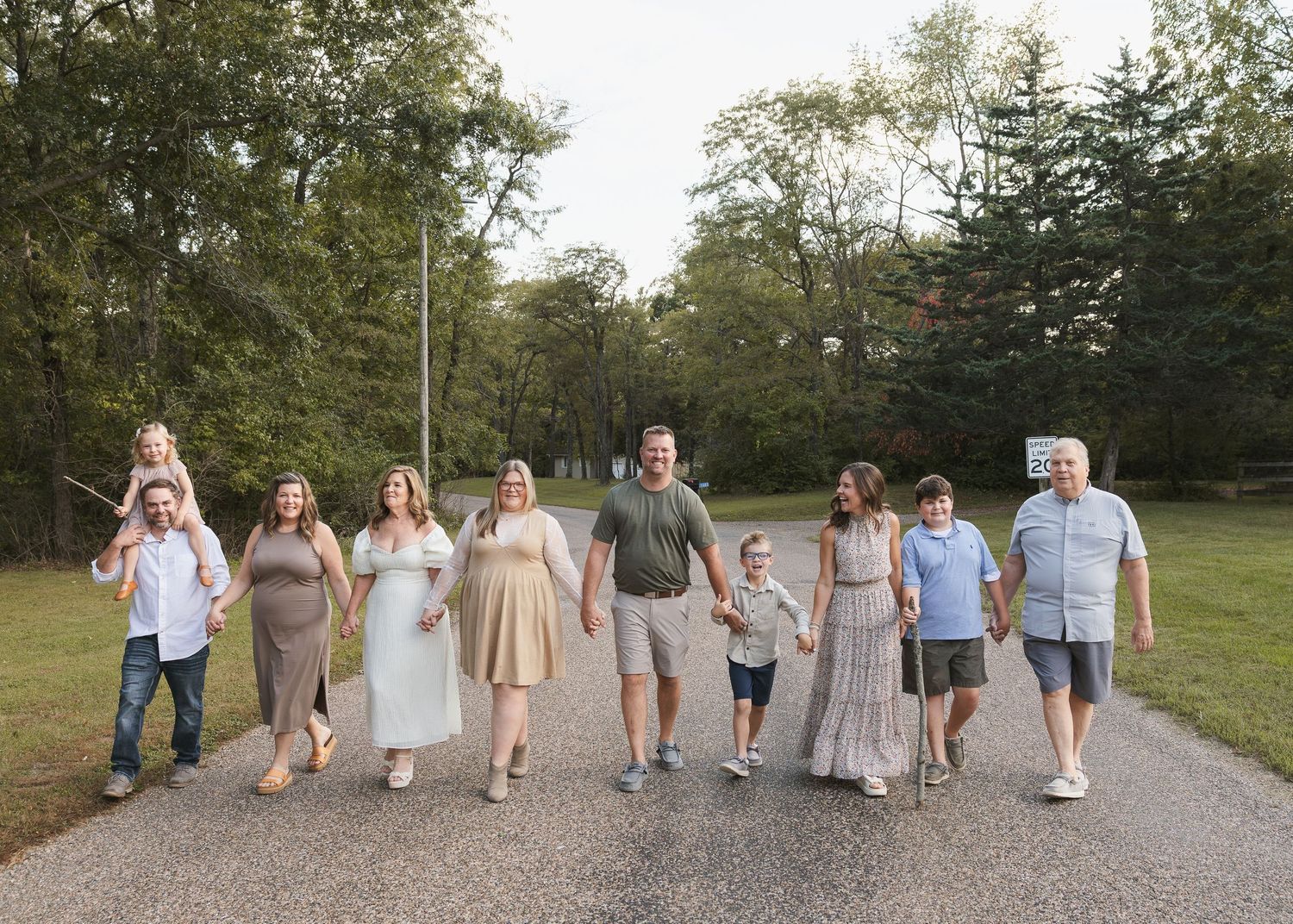 Large group walking together on a gravel path through a park setting.