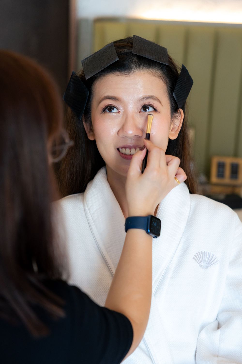 Wedding makeup session showing artist carefully applying cosmetics to client.