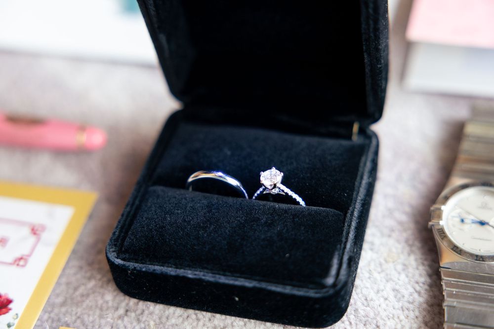A black velvet engagement ring box sits open against a light colored wooden surface.