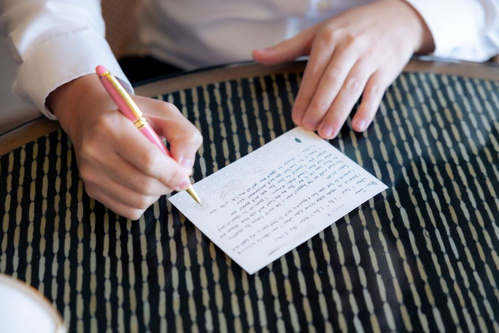 A person's hands writing handwritten notes on paper with a pen during preparations.