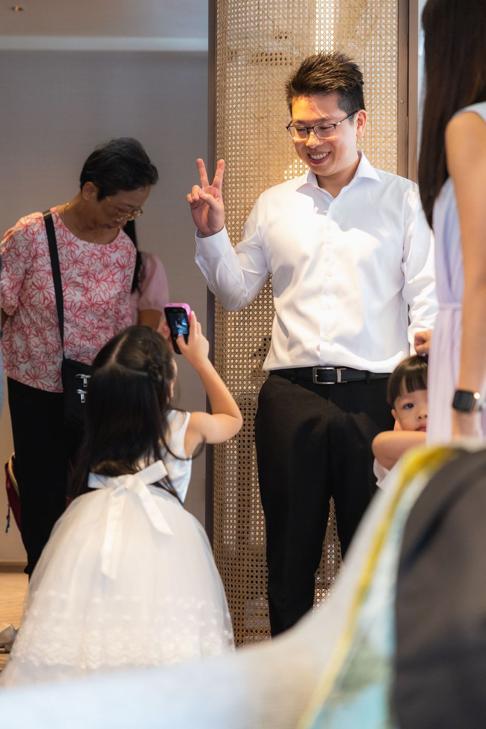 Wedding preparations showing attendants helping with formal attire in an elegant dressing room.