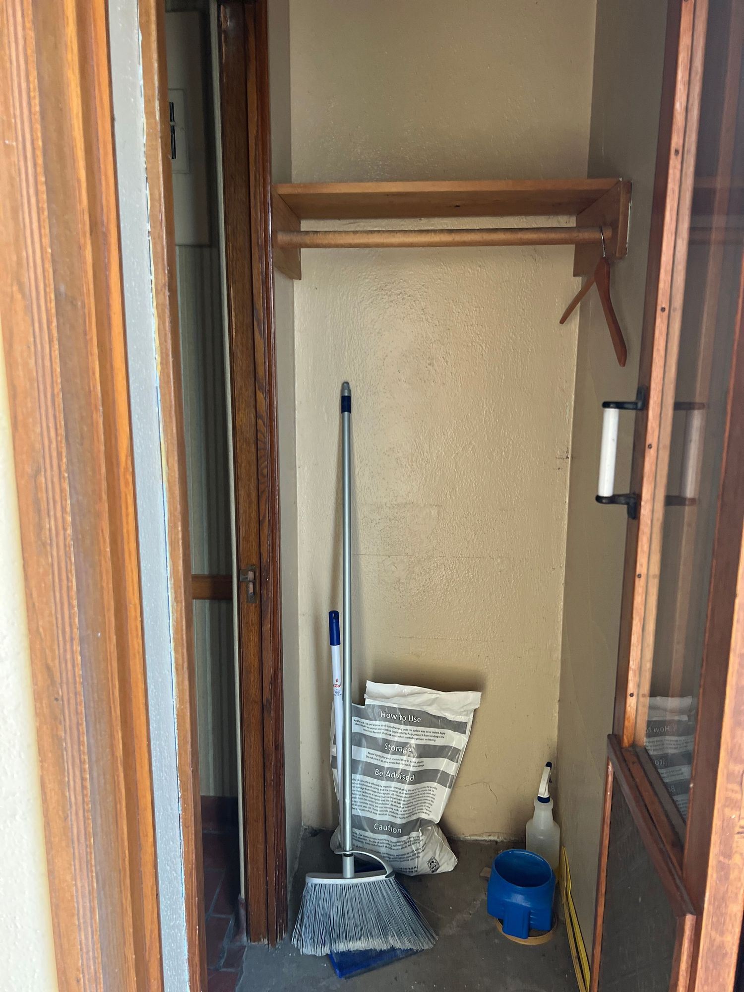 Wooden framed closet or storage space with cleaning supplies visible.