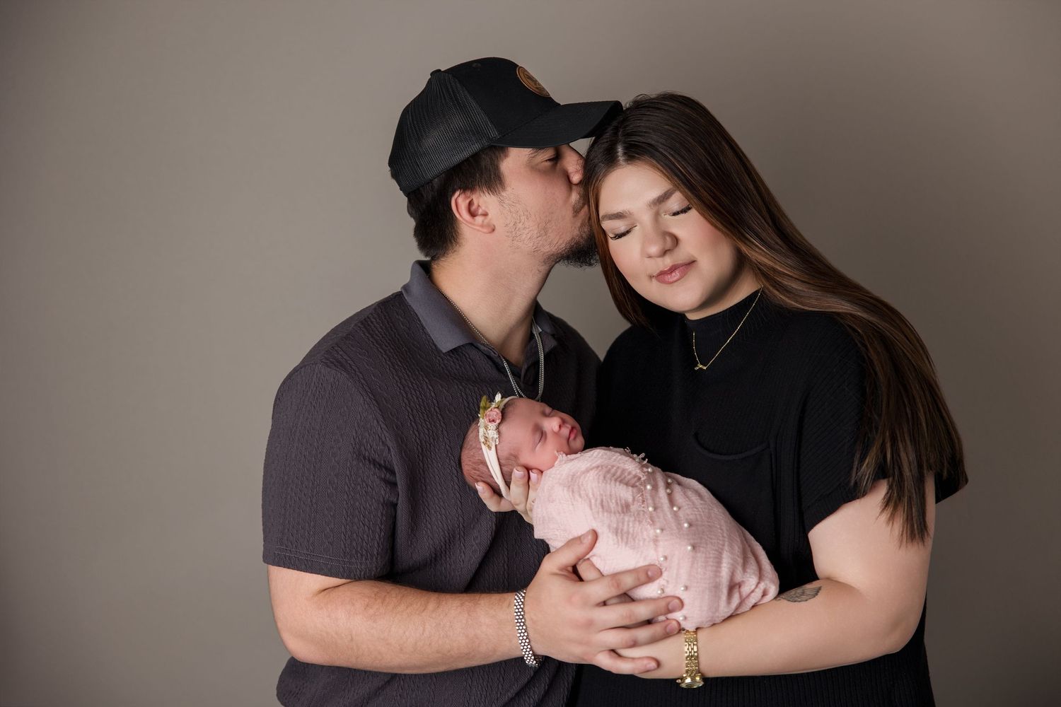 A sequence of intimate family moments showing parents bonding with their newborn baby against a dark background.