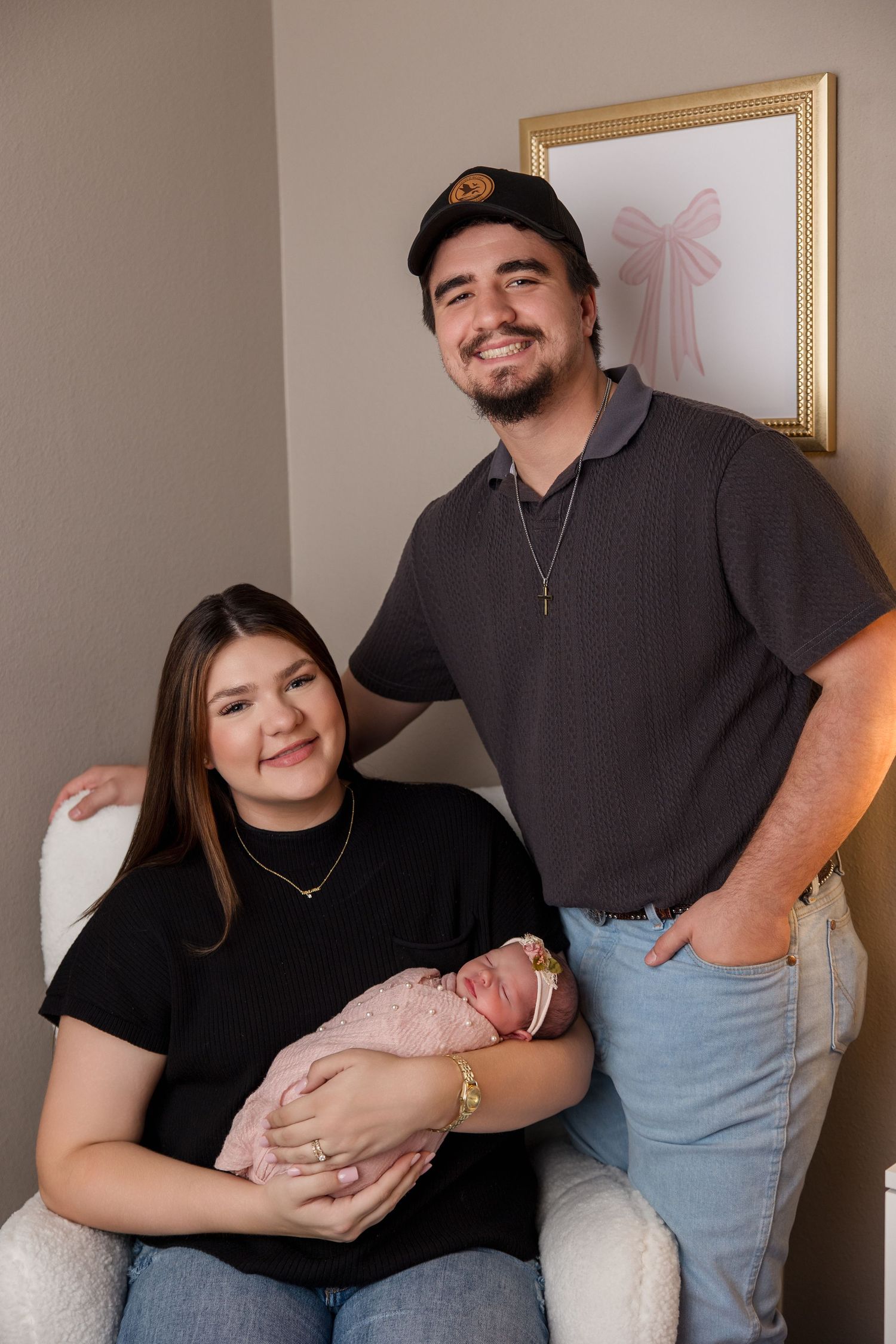 Parents pose together with their newborn baby for studio family portraits on neutral background.