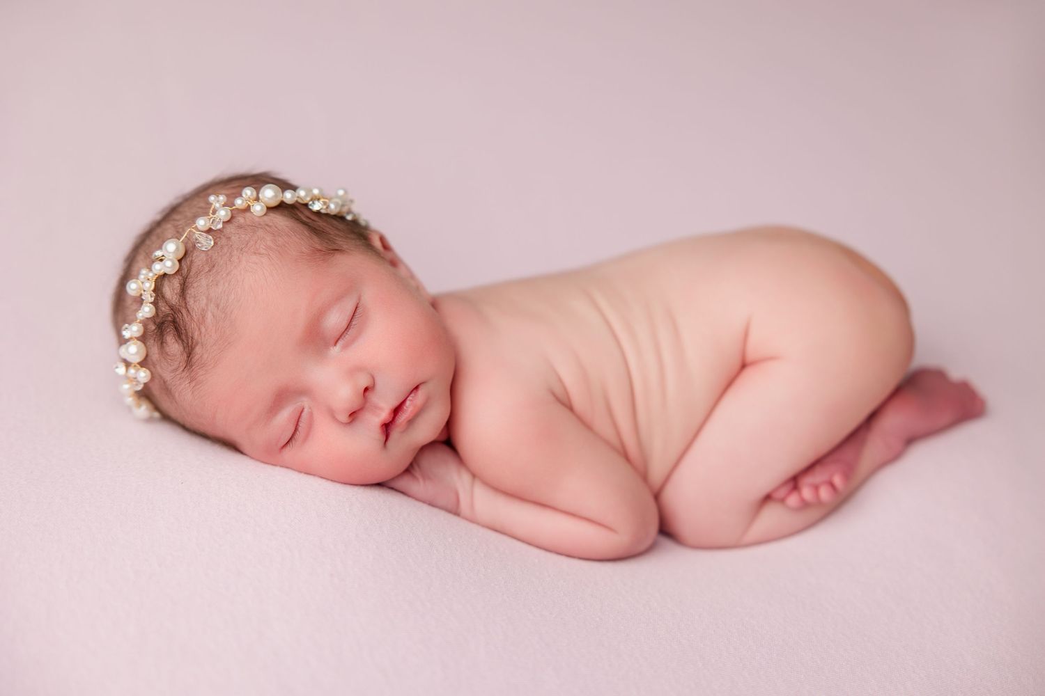 A series of artistic newborn portraits showing peaceful sleeping poses on a pale pink backdrop.