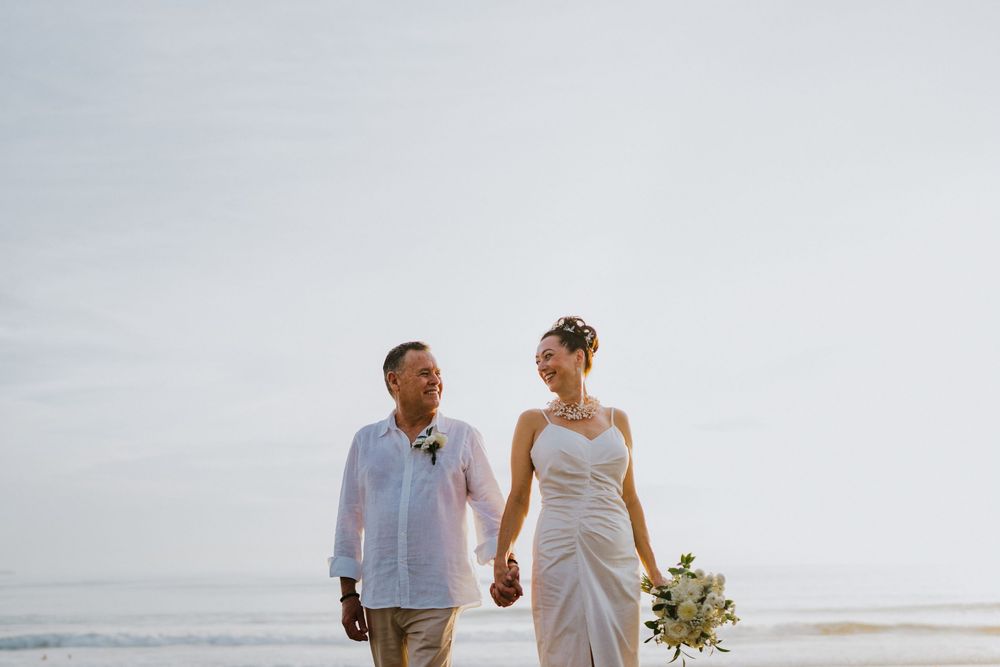 Couple strolling along a pristine beach with gentle waves in the background.