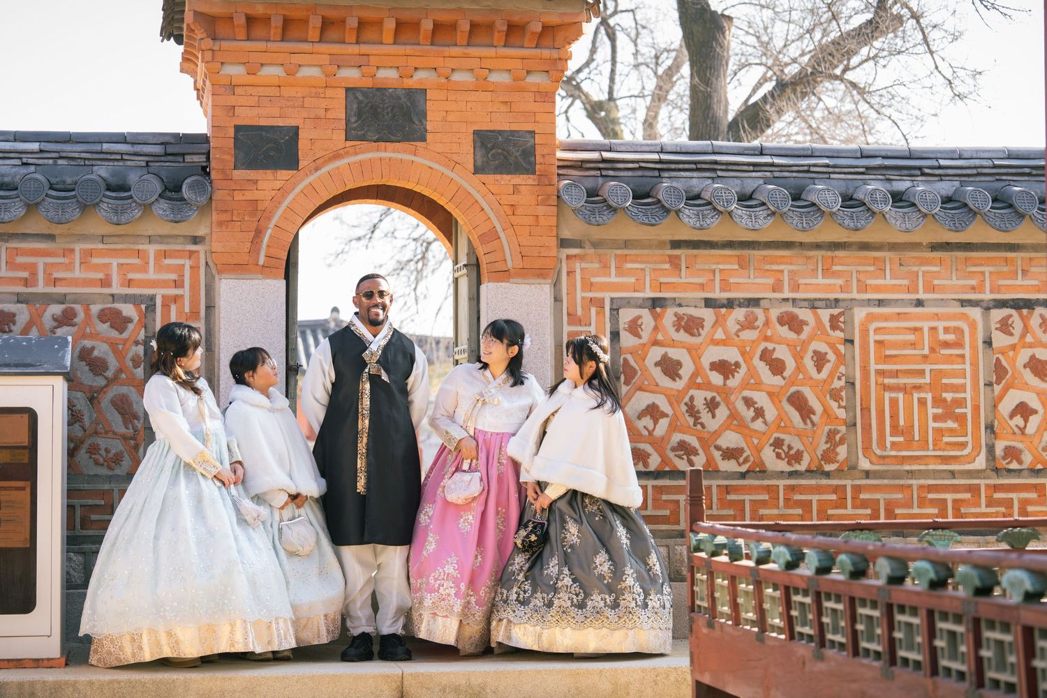 People in colorful hanbok attire walking through traditional Korean palace grounds.