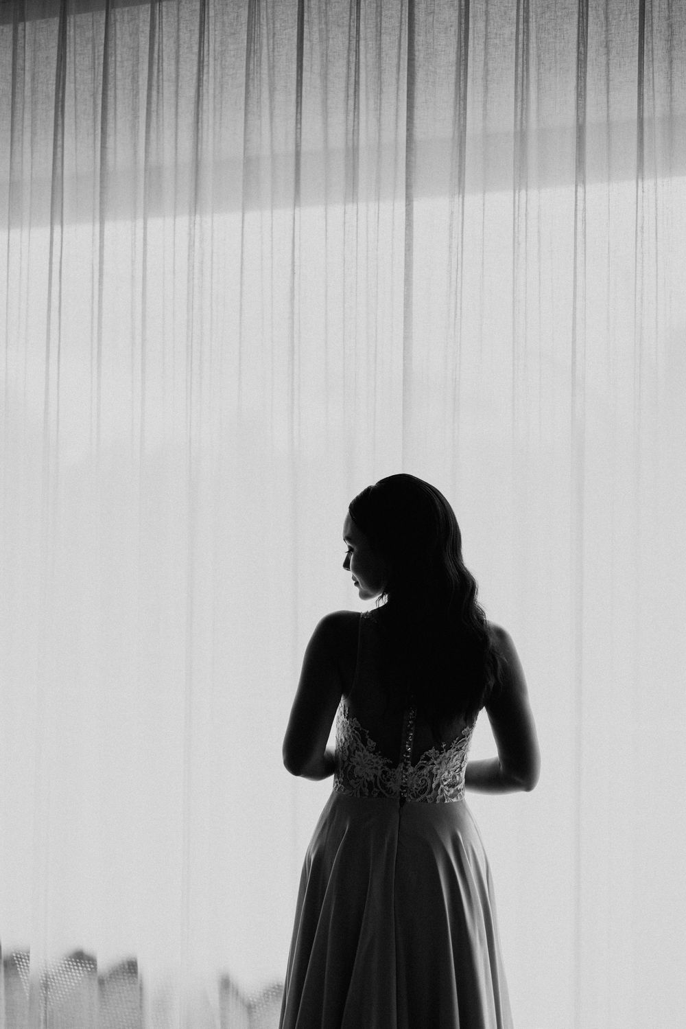 Artistic silhouettes of a wedding dress against a white curtain background.