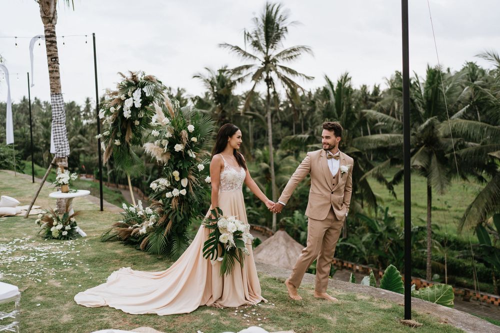Wedding celebration in a tropical garden with palm trees and scattered flower petals.