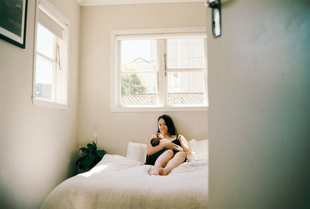 Minimalist bedroom with white walls and large windows letting in soft daylight.