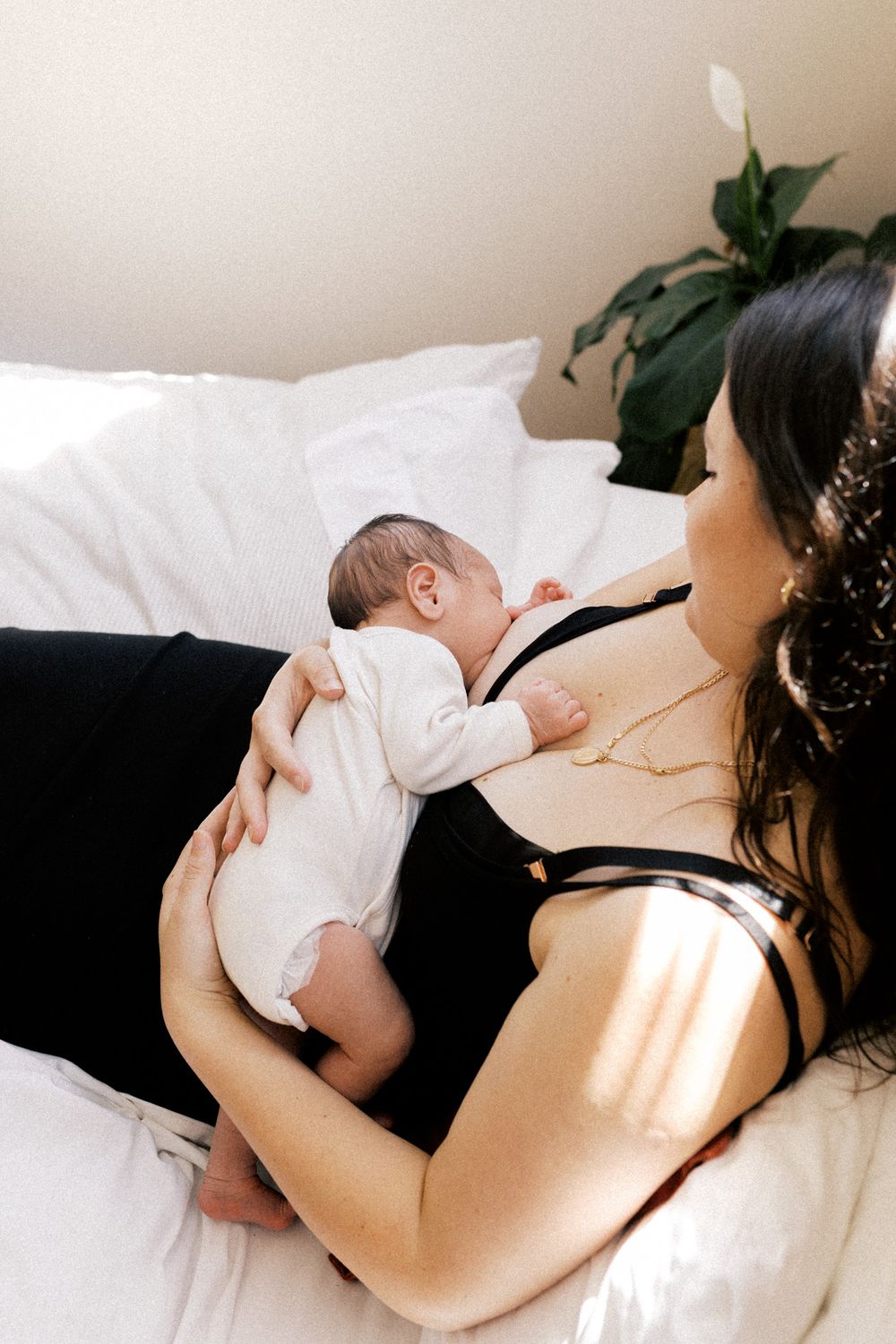 Peaceful moment of mother and baby bonding while breastfeeding on white bedding.