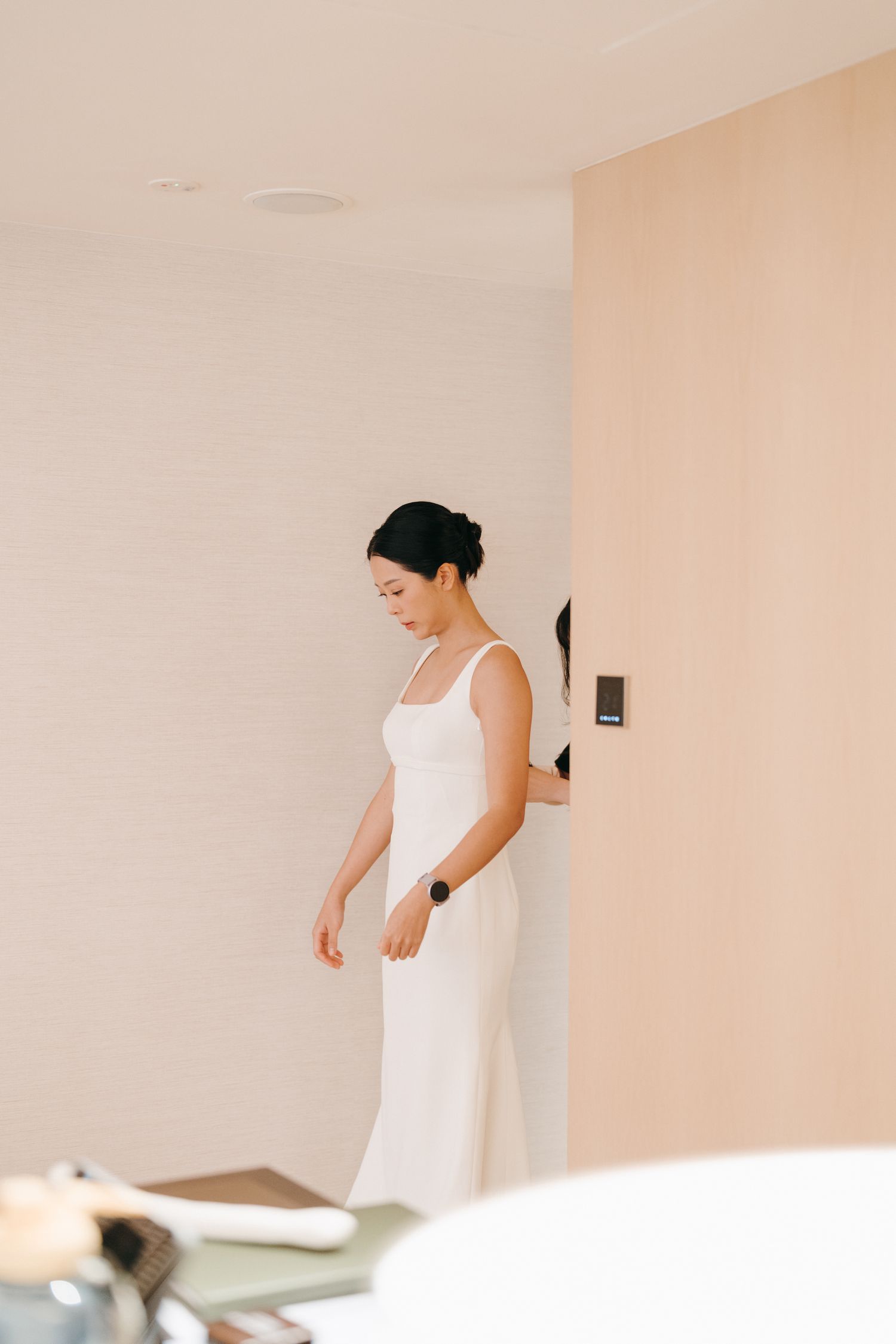 A side view of someone wearing a sleek white wedding dress standing in an elegant room.