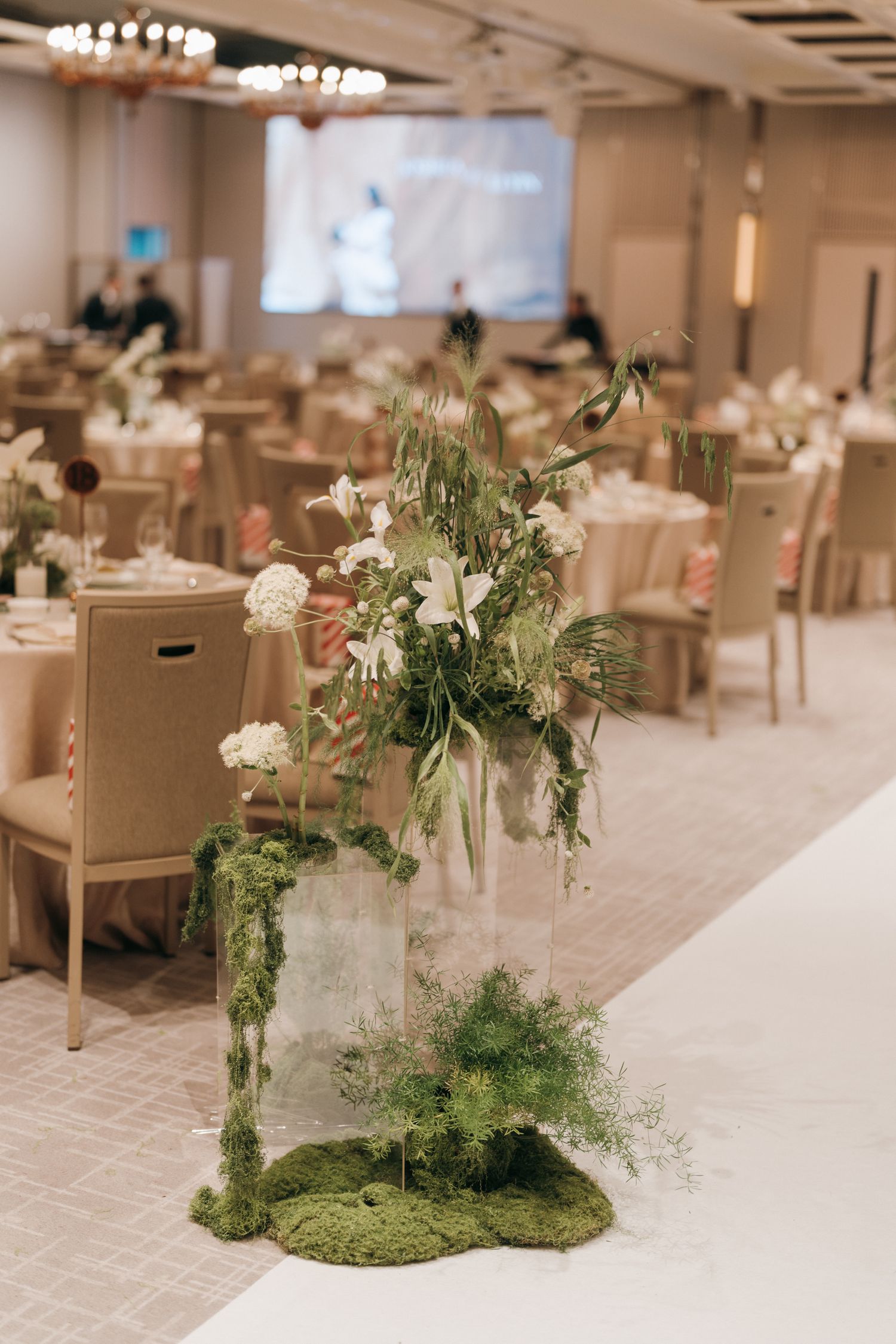 Wedding reception tables decorated with natural greenery and white floral centerpieces.