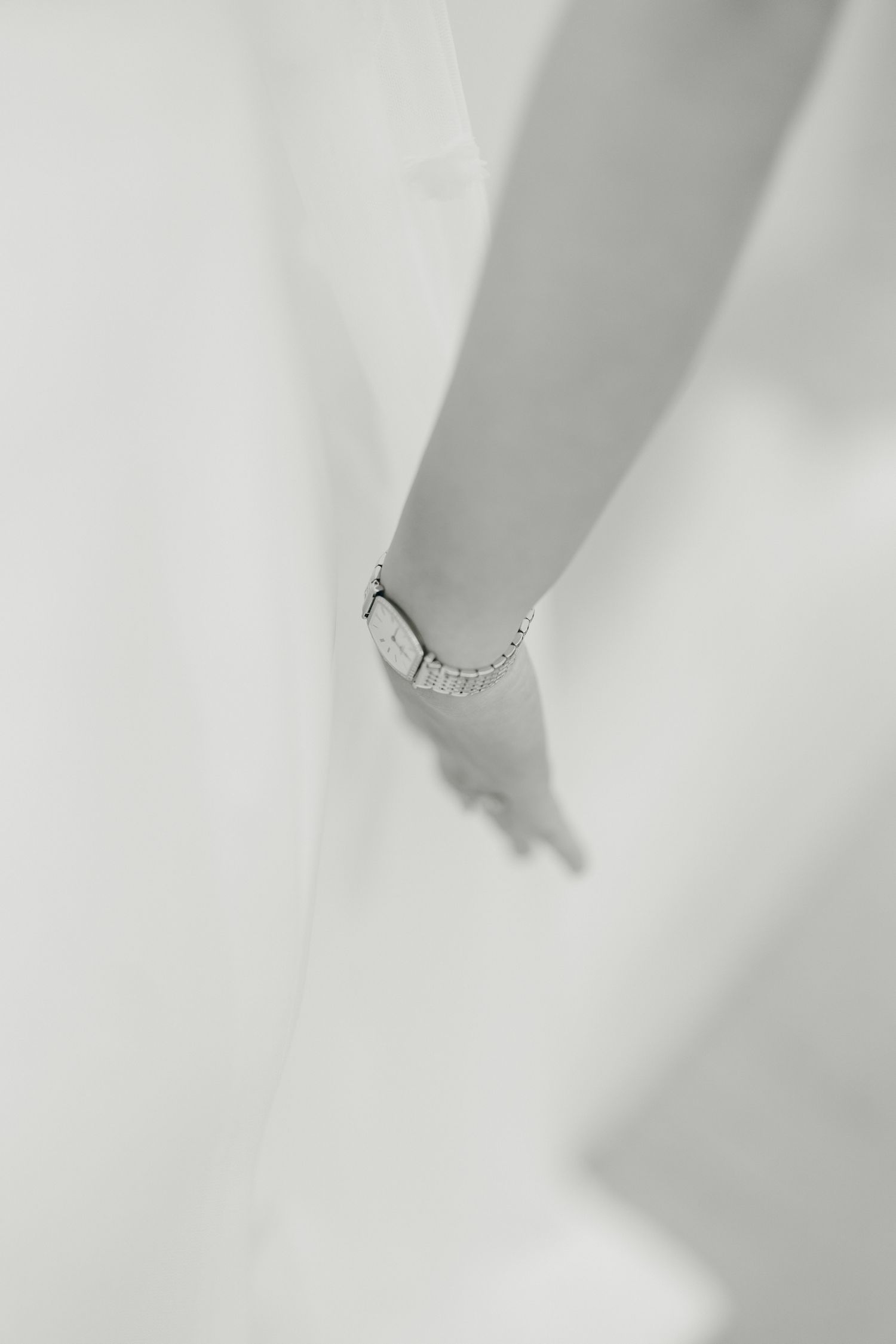 Close-up artistic shot of a delicate bridal ring against white fabric.