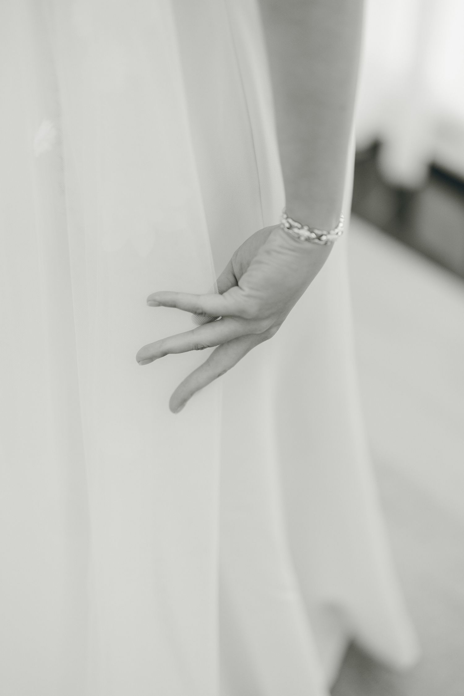 Elegant white sheer curtains gently draped with a hand delicately touching the fabric in soft natural light.
