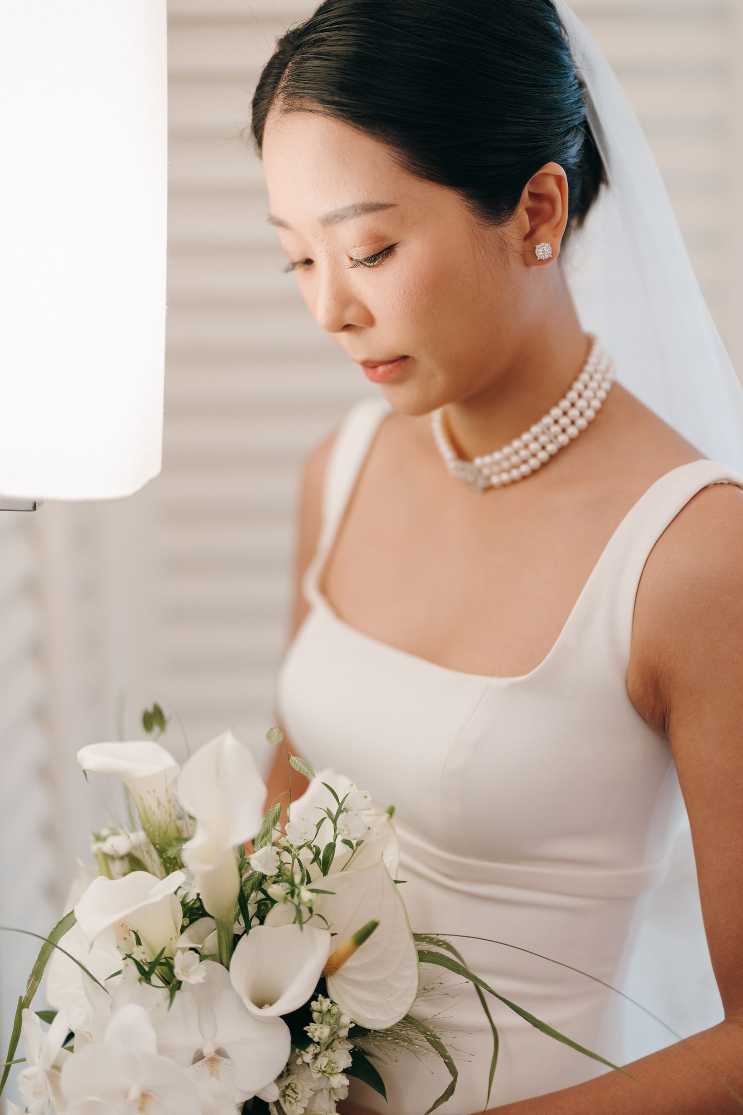 An elegant bridal portrait with white calla lily bouquet and pearl necklace.
