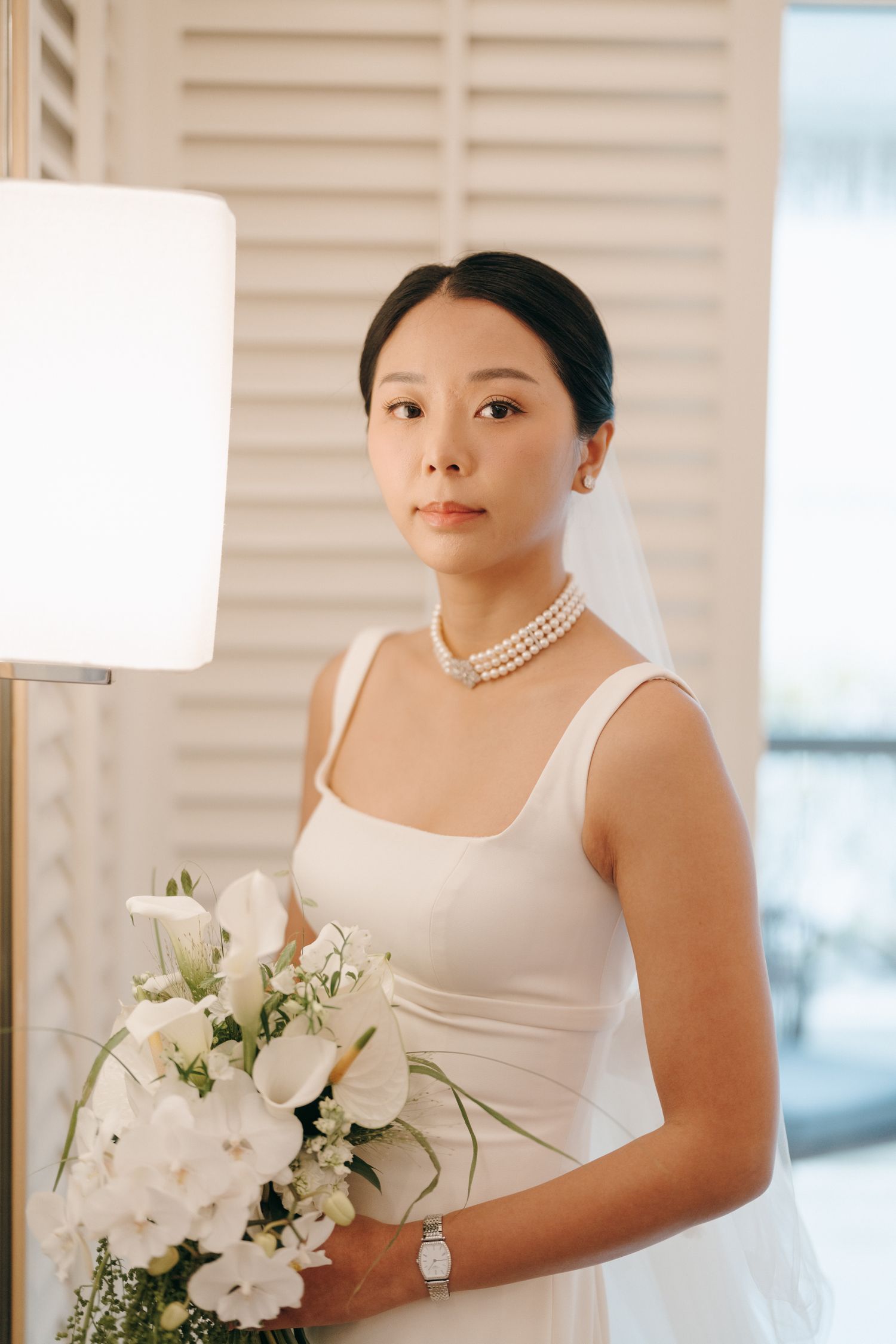 A classic bridal portrait featuring pearl accessories and a white floral bouquet.