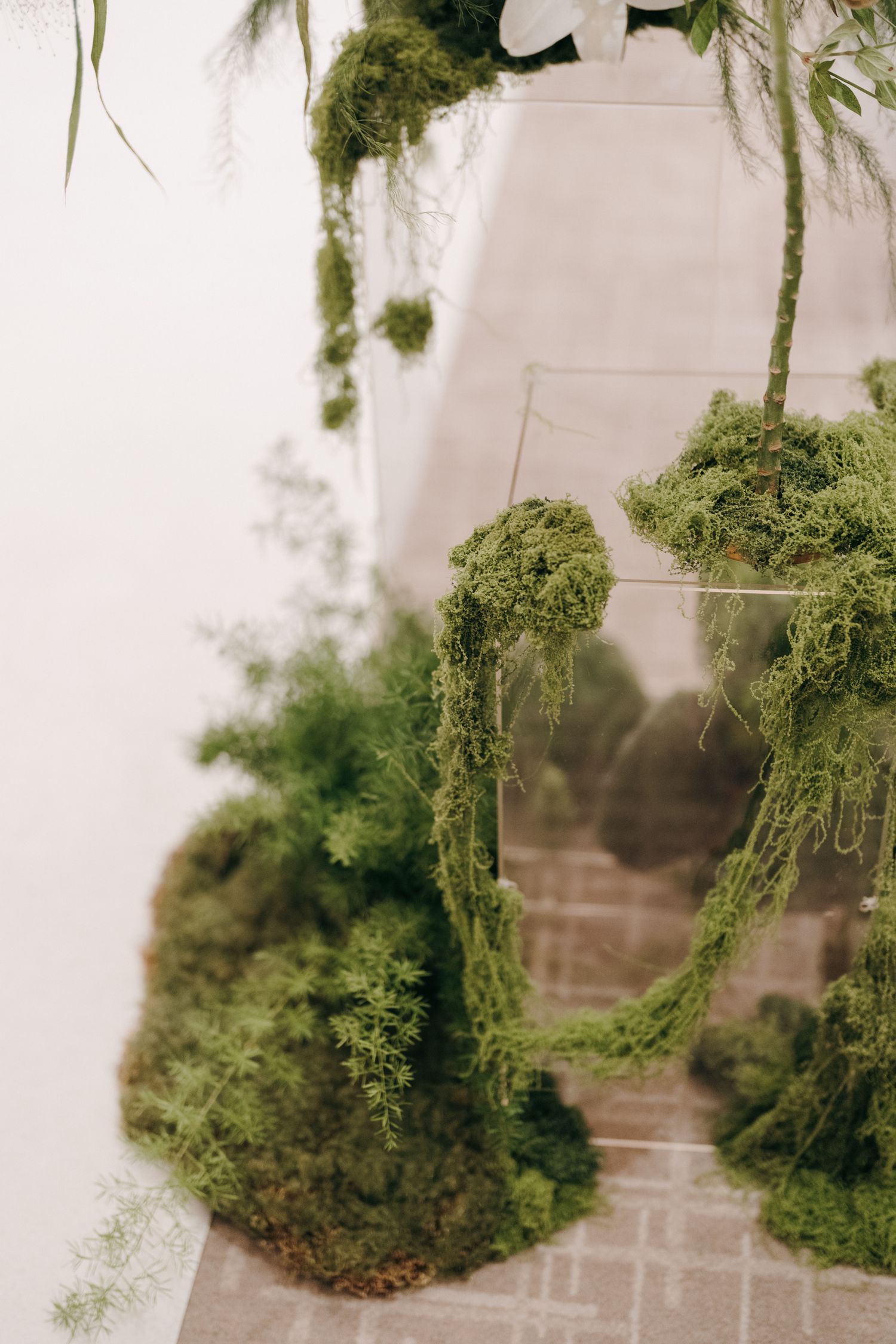 Cascading moss and greenery installation creating an organic textural display against a white wall.