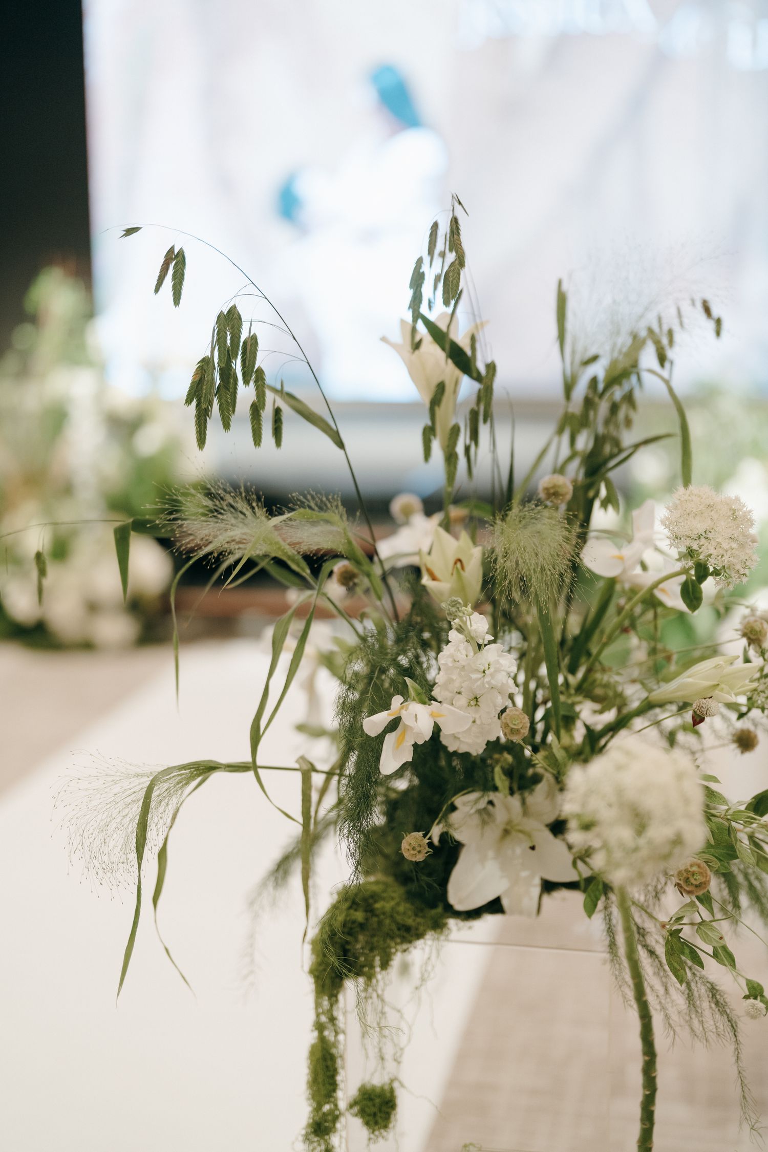 Elegant white floral arrangement with delicate wildflowers and cascading greenery in natural light.