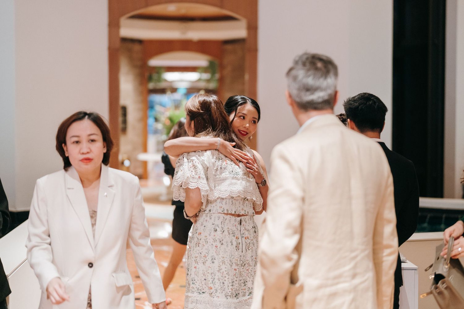 Elegant wedding guests mingling in a hallway during a formal reception.