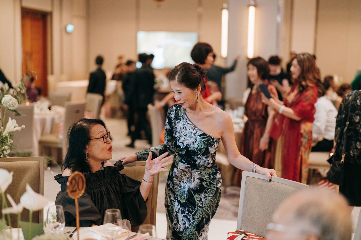 Wedding reception guests socializing at decorated tables during evening celebration.
