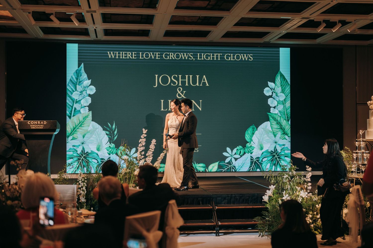 Church service with stage lighting and decorative floral arrangements in a modern worship space.