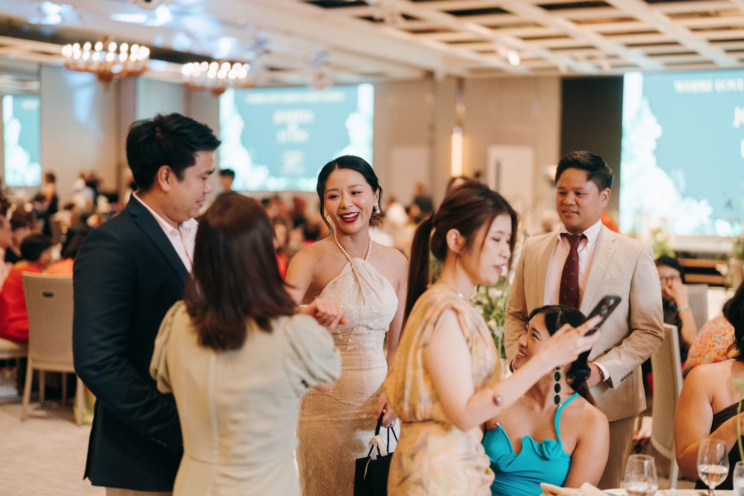 Wedding guests dance and celebrate together on a dance floor at an indoor reception venue.